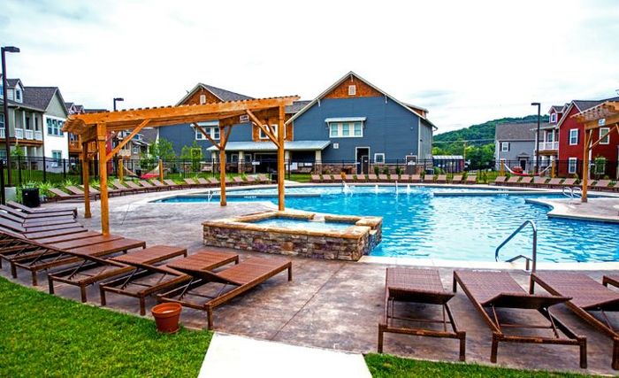 Inviting outdoor pool area with elegant pergola and comfortable loungers, surrounded by charming houses and scenic views.