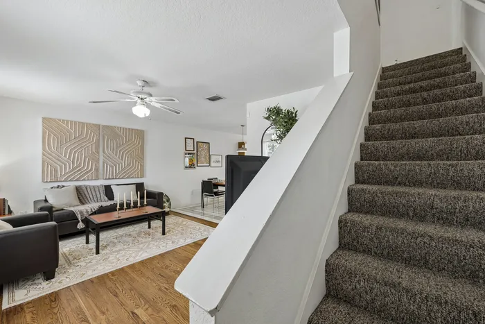 Inviting living space with elegant decor, cozy seating arrangement, and carpeted stairs leading to an upper floor.