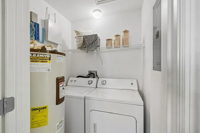Efficient laundry room with modern washer and dryer, water heater, and stylish shelving for practical living.