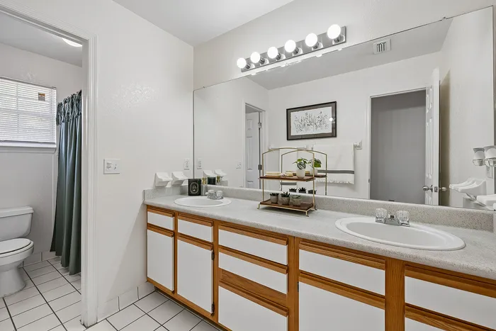 Bright and inviting bathroom featuring dual sinks, elegant cabinetry, and ample countertop space.