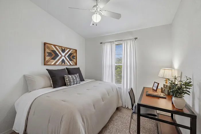 Cozy and bright bedroom featuring a comfortable bed, stylish decor, and a functional workspace perfect for productivity.