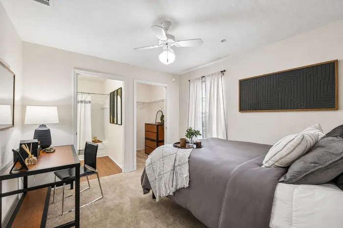 Inviting bedroom interior with cozy bed, elegant wall art, writing desk, and ensuite bathroom. Soft lighting creates a warm ambiance.