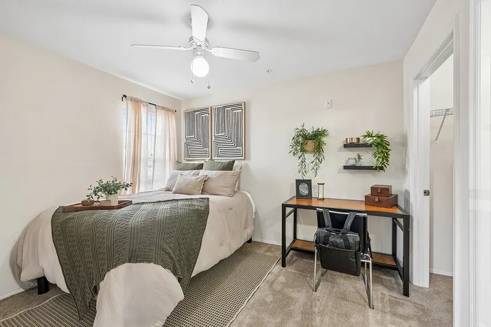 Charming bedroom with a cozy bed, stylish decor, and a modern workspace featuring lush greenery and natural light.