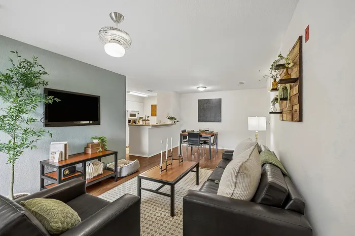 Chic open-concept living room with modern decor, leading into a cozy kitchen and elegant dining area, ideal for stylish entertaining.