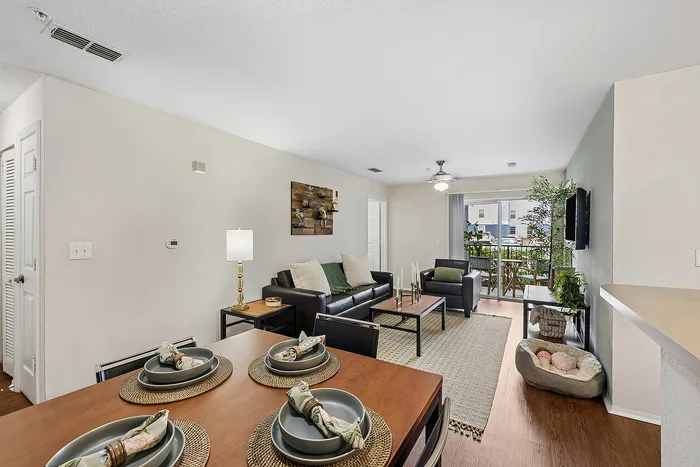 Contemporary open-plan living room with elegant dining set, cozy seating area, and abundant natural light from large windows.