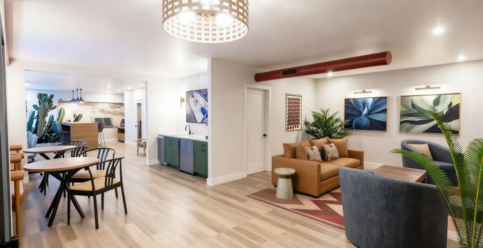 Contemporary open-plan living space with stylish seating area, vibrant artwork, and lush greenery for a welcoming atmosphere.