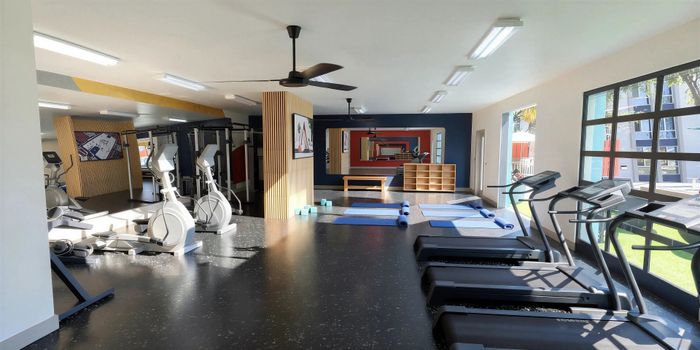 Bright and modern fitness center featuring state-of-the-art cardio equipment, weight training machines, and a spacious yoga area with mats and exercise blocks.