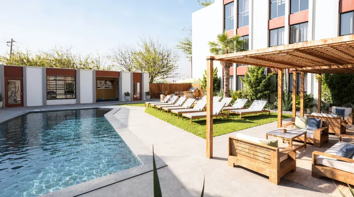 Inviting outdoor pool area with modern sun loungers, lush landscaping, and a stylish pergola perfect for relaxation.