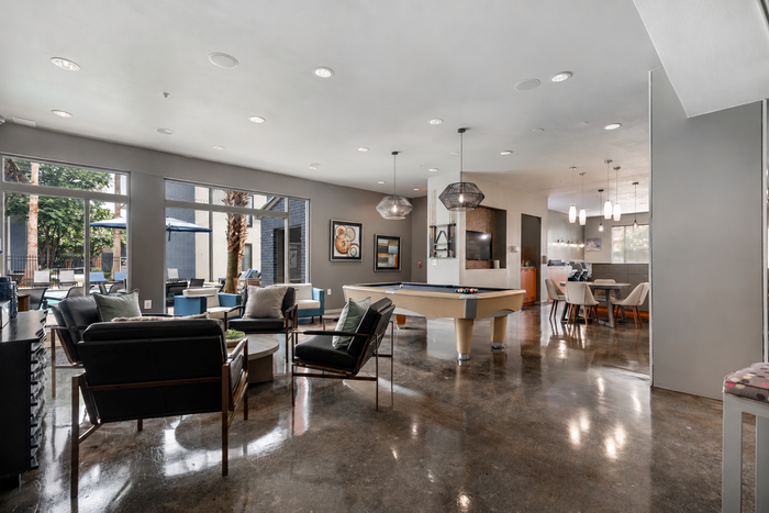 Contemporary communal lounge with pool table, cozy seating, modern decor, and an inviting open layout.