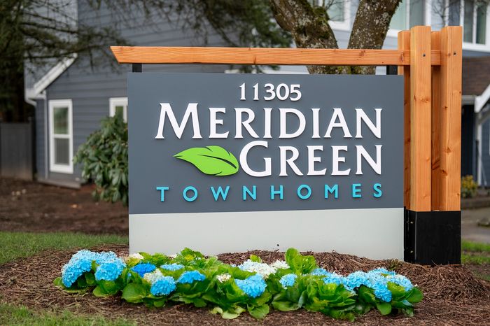 Welcome sign for Meridian Green Townhomes with vibrant hydrangeas in the foreground.