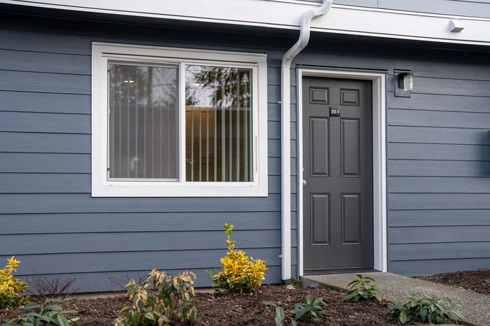 Stylish apartment exterior with modern gray siding and a welcoming front door.