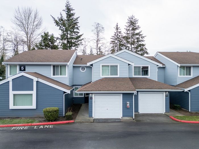Cozy suburban house with blue siding, brown roofs, and attached garages nestled in a serene neighborhood.