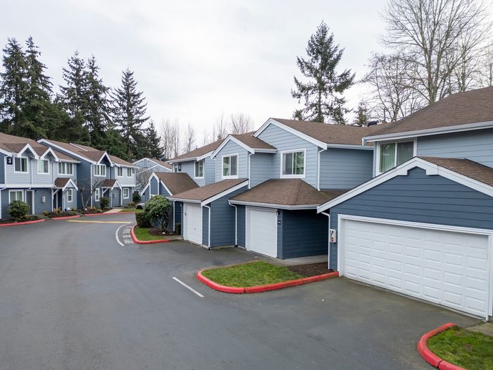 Charming suburban neighborhood with modern duplex homes featuring attached garages and lush greenery.