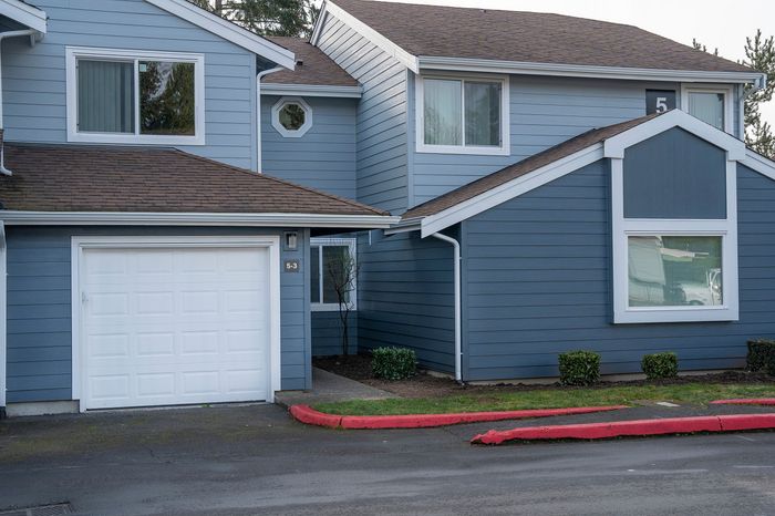 Appealing suburban home exterior with blue siding, white garage door, and neatly trimmed shrubs.