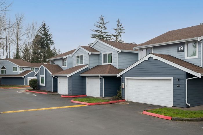 Picturesque row of modern suburban homes with blue exteriors and attached garages on a quiet street.