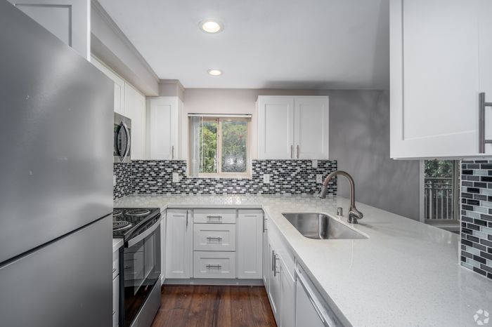 Modern kitchen with sleek stainless steel appliances, elegant white cabinetry, and stylish mosaic tile backsplash.