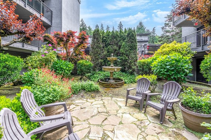 Charming garden courtyard with lush greenery, vibrant flowers, and a serene two-tiered fountain, perfect for relaxation.
