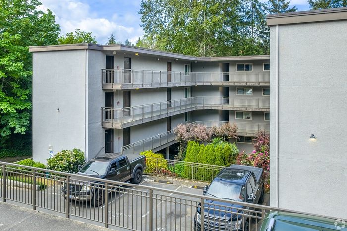 Charming apartment complex with lush greenery and ample parking in a serene location.