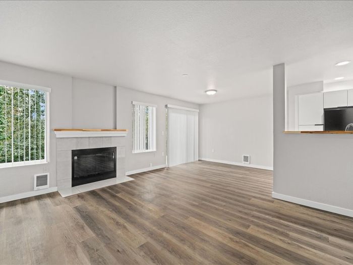 Modern open-concept living room with elegant fireplace, large windows, and sleek hardwood floors.