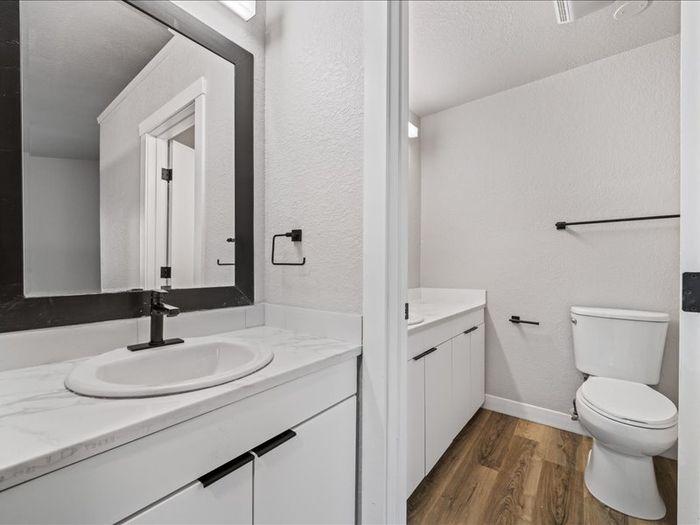 Modern bathroom with elegant marble countertop, sleek black fixtures, and hardwood flooring.