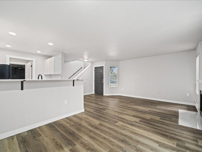 Bright open-concept living space featuring sleek hardwood floors, modern kitchen with bar seating, and stylish recessed lighting.