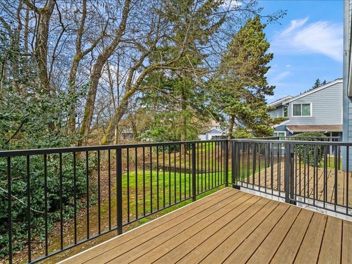 Charming wooden deck overlooking a lush green garden, perfect for enjoying serene outdoor views.