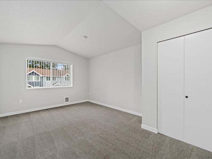 Bright and spacious bedroom with plush carpeting and large window offering scenic views, perfect for comfortable living.