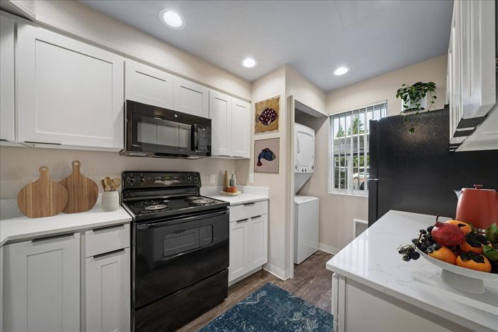Modern kitchen with sleek appliances, bright white cabinetry, and a cozy laundry nook, enhanced by natural light and decorative accents.