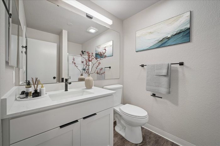 Elegant bathroom featuring a sleek vanity with modern fixtures, minimalist decor, and an artful wall piece enhancing aesthetic appeal.