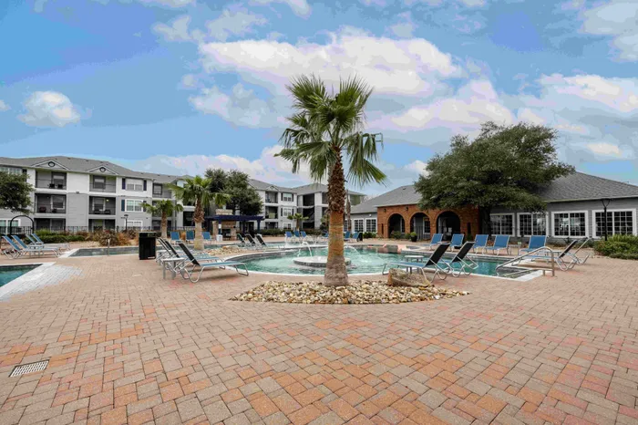 Resort-style pool with palm trees at The Zone student apartments near TAMU in College Station Texas