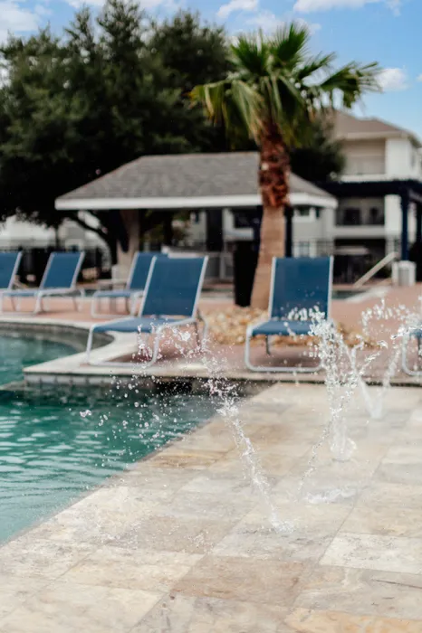 Resort-style swimming pool with lounge chairs at The Zone student apartments near Texas A&M University in College Station TX