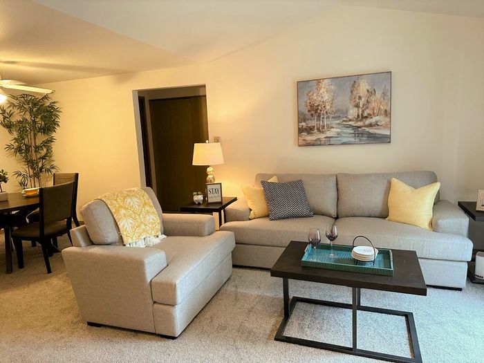 Inviting living room with plush seating, a modern coffee table, and an elegant dining area in the background.