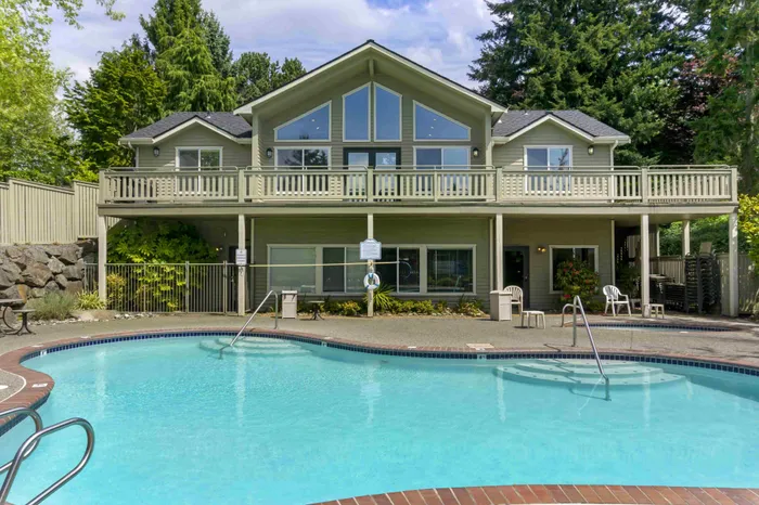 Elegant two-story house with large windows and a blue swimming pool.