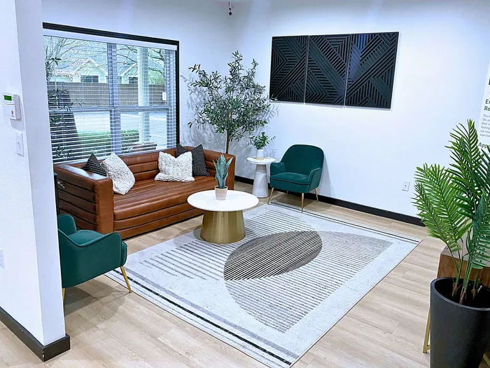 Centennial Ridge leasing office; stylish room with a modern brown leather sofa, green armchair, and elegant decor.
