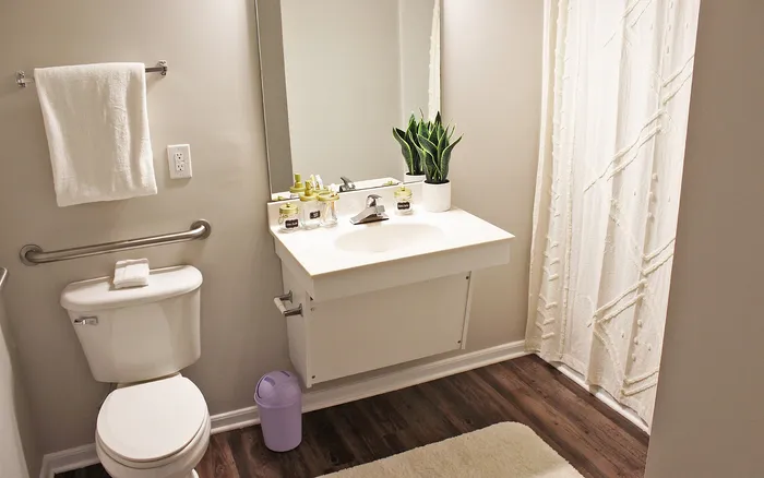 Bright bathroom featuring a sleek vanity, indoor plant, and modern fixtures located at Centennial Ridge apartments.