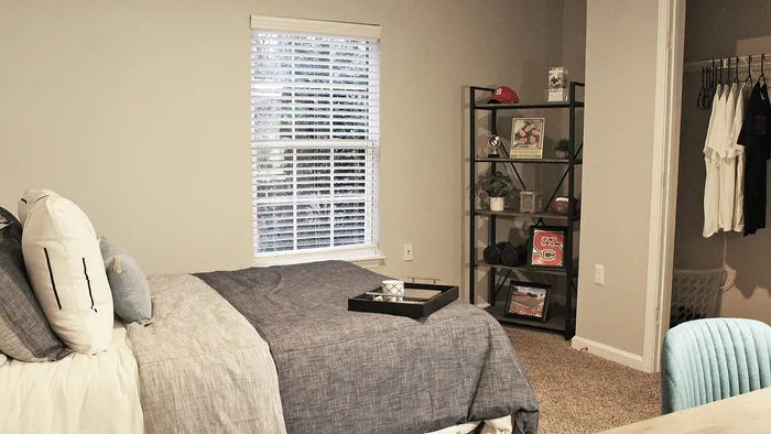 Inviting Centennial Village bedroom with stylish decor, featuring a comfortable bed, modern shelving, and natural light.