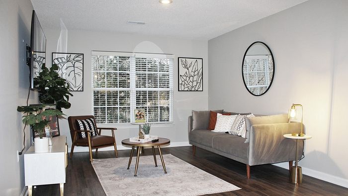 Elegant living room with stylish furnishings, featuring a grey sofa, a round coffee table, and modern decor within Centennial Village apartment.