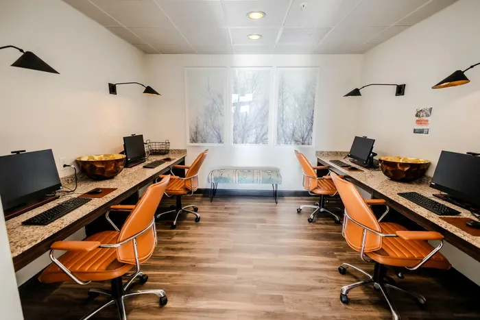 Stylish office space with sleek desks, modern computers, and elegant orange chairs.