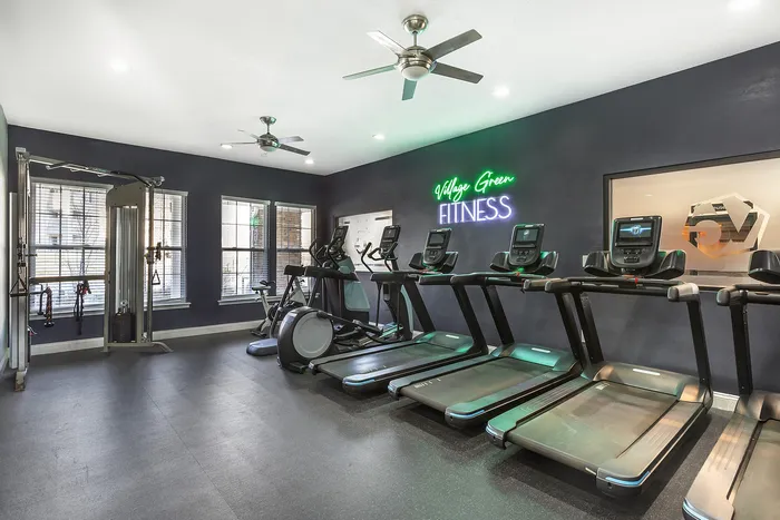 Contemporary gym with treadmills, stationary bike, and weight machines in a sleek fitness center Village Green in Raleigh, North Carolina.