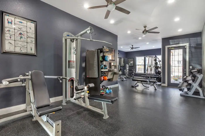 Spacious gym with modern equipment, weight racks, and bright interior lighting. at Village Green in Raleigh, North Carolina.