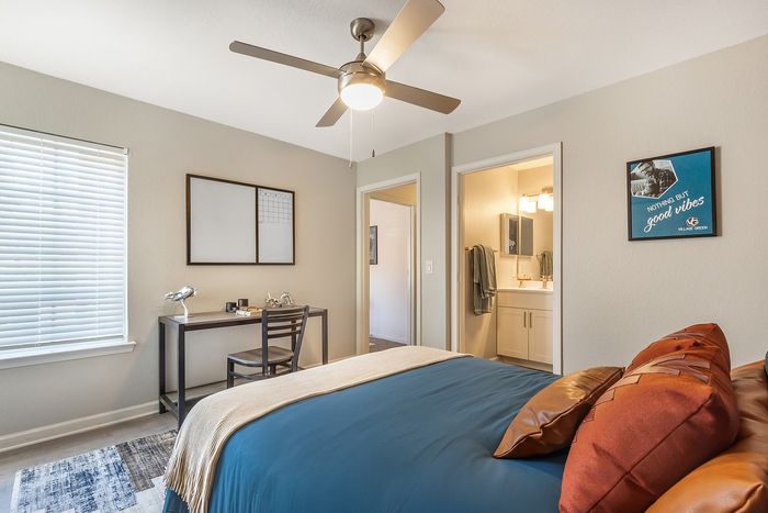 Inviting bedroom featuring soft lighting, stylish decor, and a compact workspace at Village Green in Raleigh, North Carolina.