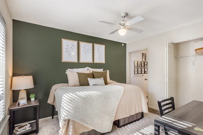 Inviting bedroom with a plush bed, elegant decor, and natural light at Village Green in Raleigh, North Carolina..