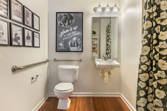 Stylish bathroom with floral shower curtain, modern fittings, and decorative wall art at Village Green in Raleigh, North Carolina.
