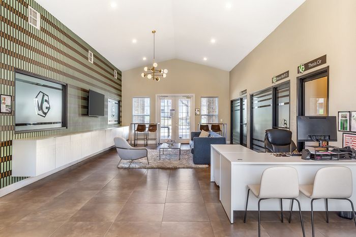 Modern apartment lobby featuring chic furniture, a sleek reception desk, and ambient lighting at Village Green in Raleigh, North Carolina.