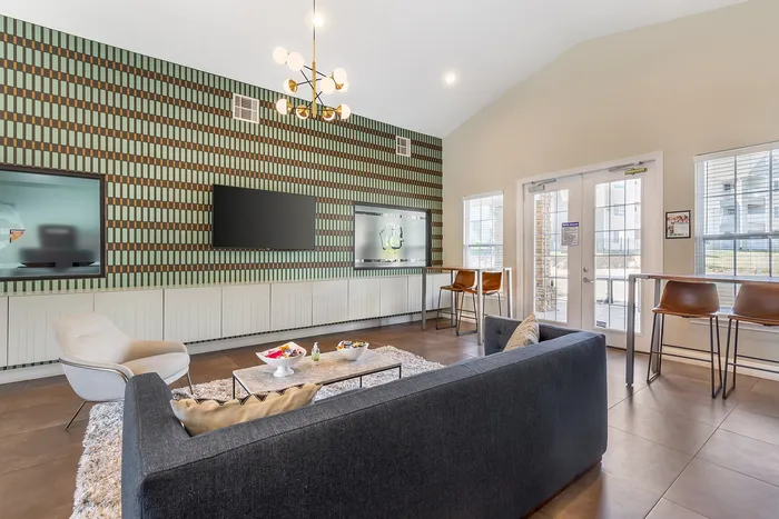 Stylish lounge area with modern seating, patterned accent wall, and natural lighting Village Green in Raleigh, North Carolina.