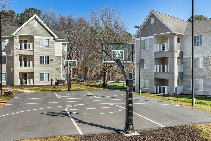 Inviting apartment complex with a basketball court set against a backdrop of treesVillage Green in Raleigh, North Carolina.