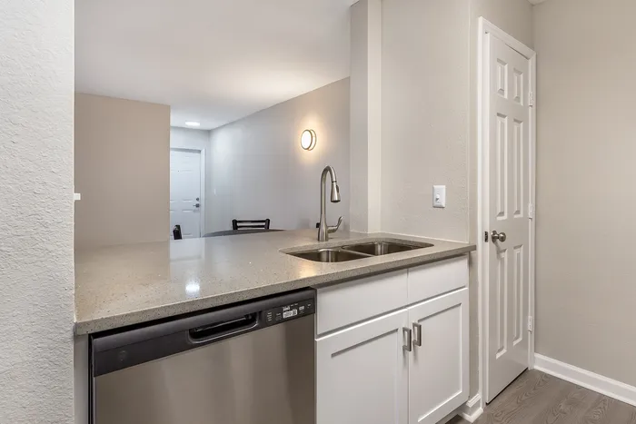 Modern kitchen with sleek countertops, dual sinks, and white cabinetry at Village Green in Raleigh, North Carolina.