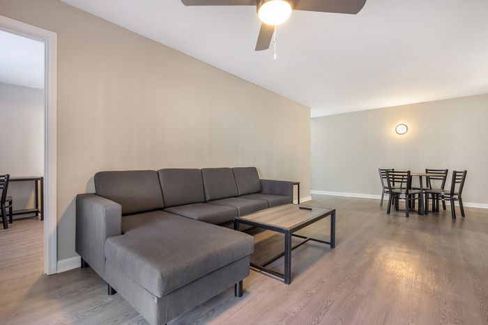 Bright living room with modern gray sectional sofa and sleek dining area at Village Green in Raleigh, North Carolina.