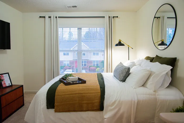Inviting bedroom featuring a plush bed with layered pillows and a stylish tray under soft lighting.
