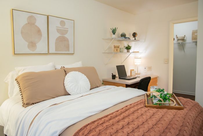 Inviting bedroom with stylish decor, featuring a comfortable bed, modern artwork, and functional workspace.